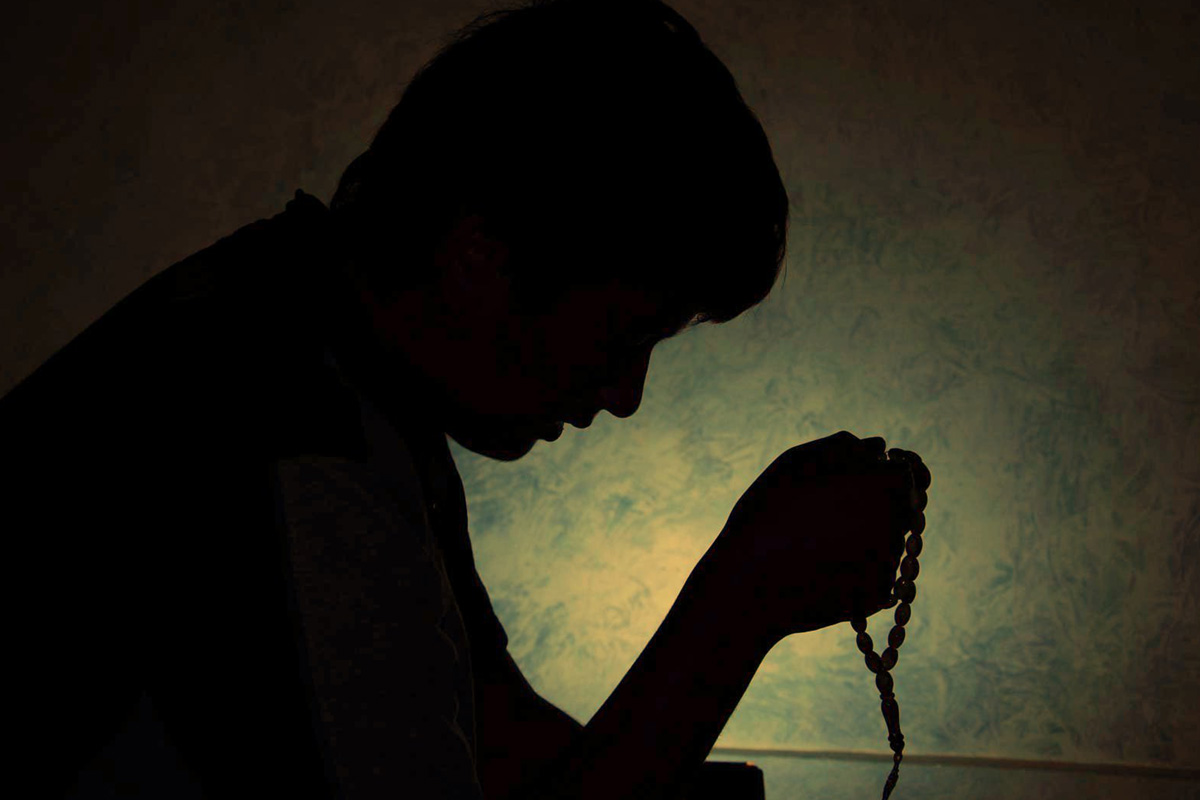 silhouette of a man holding a rosary