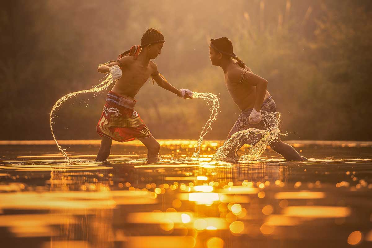 two boys wrestling in a river