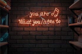 neon letters that say 'you are what you listen to'