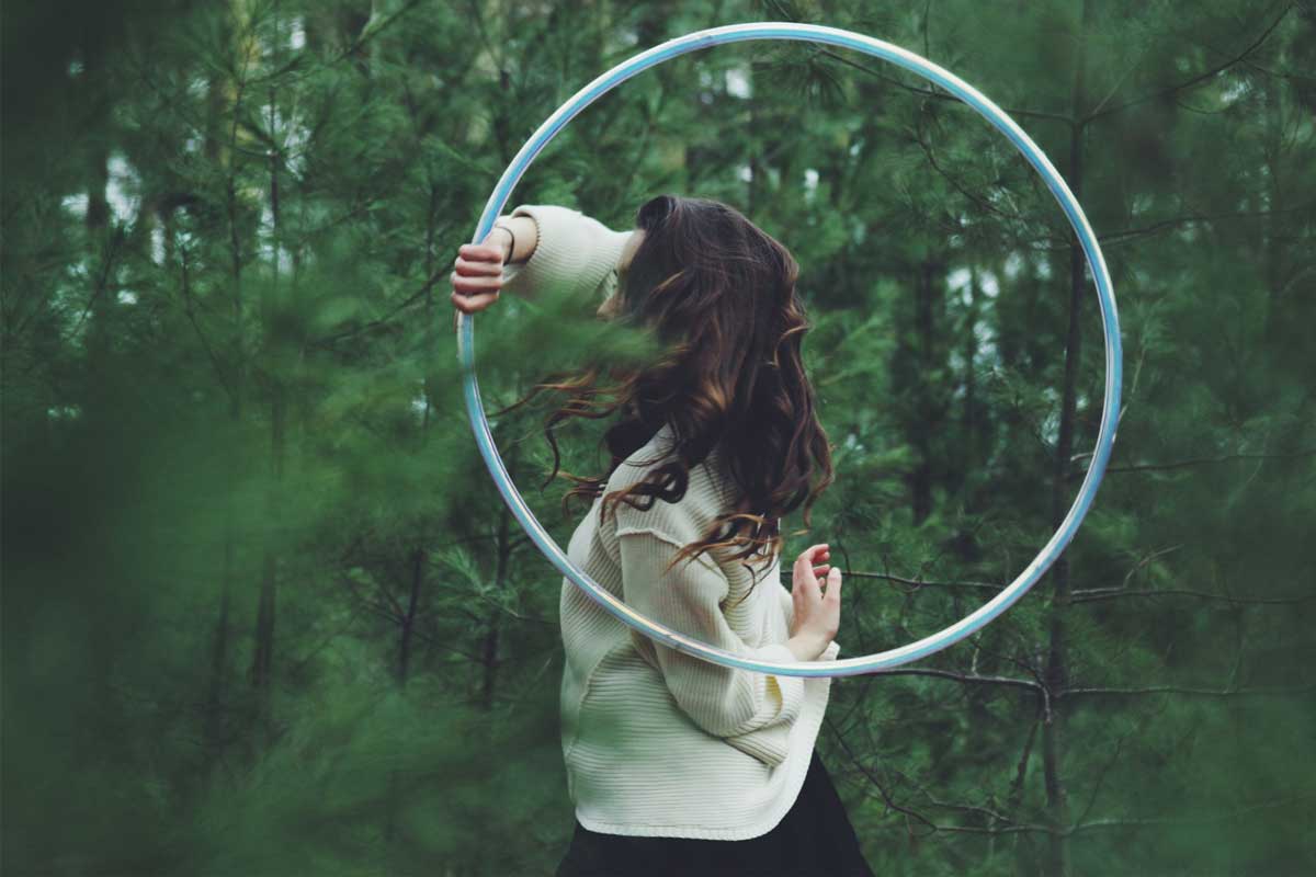 girl spinning a hula hoop in the woods