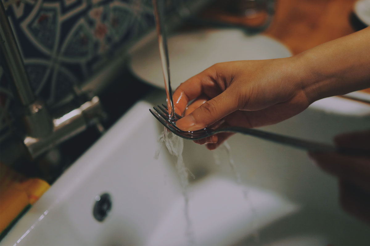 hand washing a fork in a sink